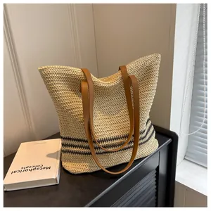 Close-up of beige woven tote with black stripes and brown leather straps in soft sunlight