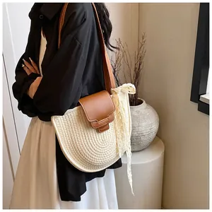 Détail d'un sac bandoulière tissé demi-lune avec rabat en cuir et ruban de dentelle