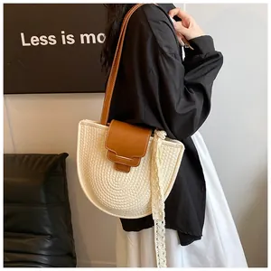 Détail de la texture tissée main et bandoulière en cuir marron sur sac de plage crème