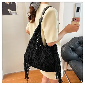 Detail of black woven cotton shoulder bag featuring boho fringe and hollow texture
