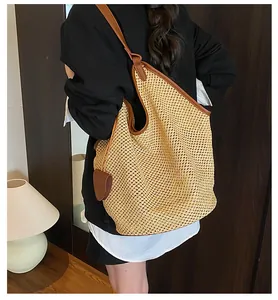 Detailed view of spacious straw tote bag with brown leather straps and heart charm