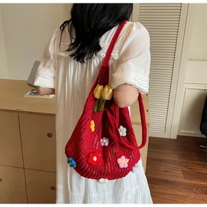 Detail of red crochet tote bag with colorful 3D knitted flowers and openwork mesh texture