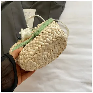 Close-up of woven straw bag with crochet flowers and elegant white pearl chain strap