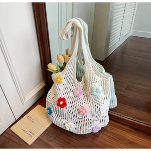 Detail view of a handmade crochet tote bag with colorful 3D floral accents on wooden floor
