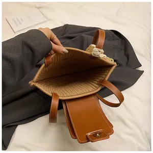 Détail d'un sac en paille avec rabat en cuir marron et bordure en dentelle blanche