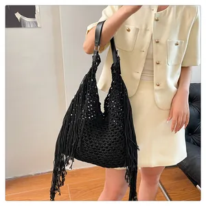 Detail of a black woven crochet bag with long fringe and adjustable leather strap