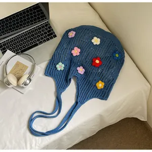 Detail view of a blue crochet tote bag with colorful 3D floral knit decorations