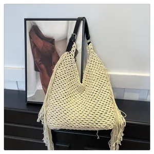 Detail of bohemian cream crochet beach tote with long fringes and black leather strap