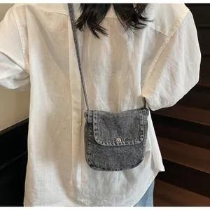 Close-up of vintage grey denim messenger bag showing textured fabric and metal buckle