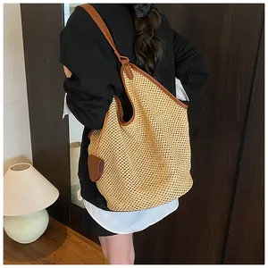Detail of woven straw tote bag with brown leather shoulder straps and side trim detail