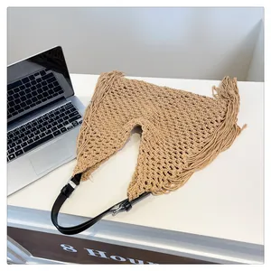 Detailed macro view of bohemian hollow-out woven tote bag with fringe and black leather strap
