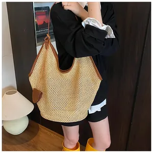 Close-up of a large straw tote bag with brown leather trim and shoulder straps