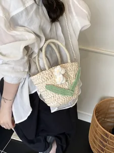 Woven straw handbag with crochet flowers and pearl strap shown on model for summer