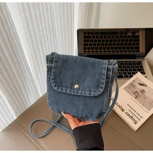Detail view of a vintage denim crossbody bag with silver buckle and stitched texture