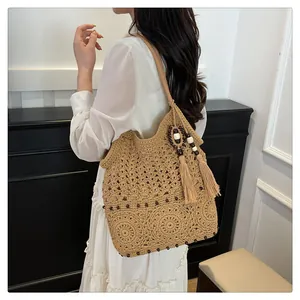 Detail of hollow floral knit cotton shoulder bag with black beads and tassel charms