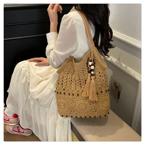 Detail of bohemian cotton woven shoulder bag with floral hollow patterns and beaded tassels