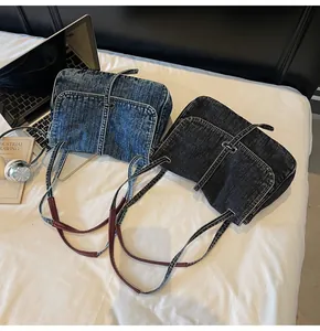 Detail view of denim messenger bags in blue and black with buckled flap and strap