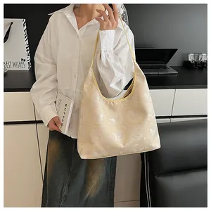Detail of elegant cream hobo bag with delicate butterfly embroidery and glossy finish