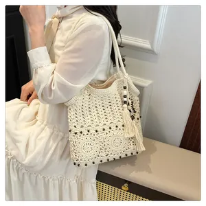 Detailed close-up of ivory cotton crochet beach bag with wooden beads and long tassels
