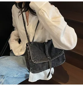 Detail of black washed denim crossbody bag featuring silver buckle and vintage texture