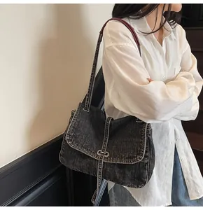 Detail of vintage washed denim shoulder bag featuring metal buckle and distressed texture