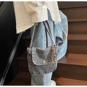Close-up of vintage grey denim messenger bag with silver button on a wooden staircase