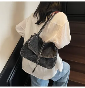 Black denim messenger bag shown on model for a trendy oversized casual shoulder look