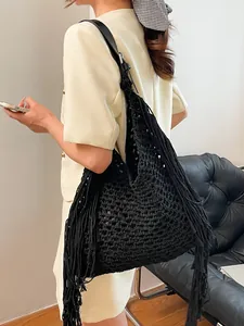 Black handmade crochet hobo bag with long tassels and leather strap shown on a model
