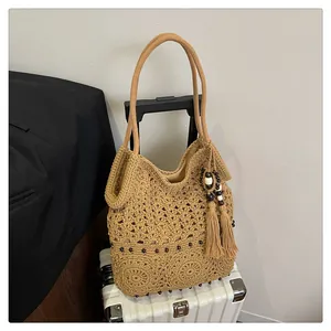 Detail of hollow-out floral crochet tote bag with wooden beads and tassels on a suitcase