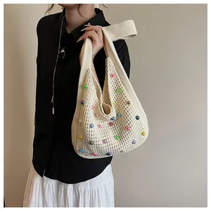 Detailed knit of a beige woven tote bag with colorful pearl accents on a model