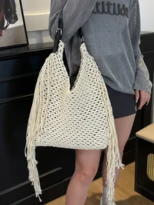 Beige hand-woven crochet tote bag with fringe details and black leather shoulder strap