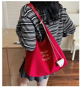 Détail du sac cabas en toile rouge avec lettrage blanc et petite pochette déco