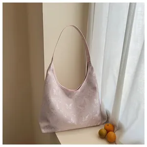Close-up of pink silk hobo bag featuring delicate white butterfly embroidery and jacquard texture