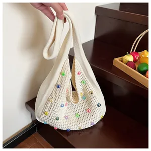 Detailed texture of ivory knit bag with colorful beads and hollow mesh pattern