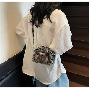 Close-up of vintage washed denim crossbody bag in dark grey with orange leather patch detail