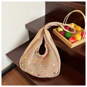 Close-up of beige knit bag featuring hollow-out crochet pattern and colorful beads