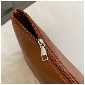 Macro shot of silver metal zipper and brown lychee grain leather on a woven tote bag