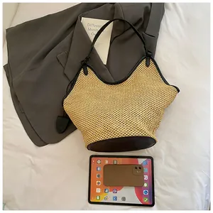 Detail of spacious straw tote bag showing black leather trim and interior capacity