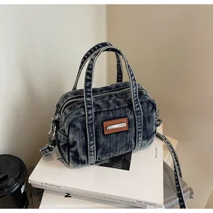 Detail of vintage blue denim boston bag with brown leather patch and metal strap hooks