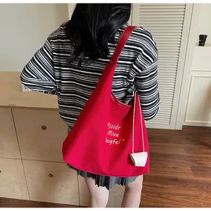 Détail du sac cabas en toile rouge avec impression de lettres et large bandoulière