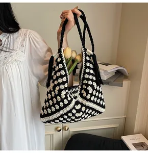 Detailed macro view of crochet pattern and tassel on black and white woven tote bag