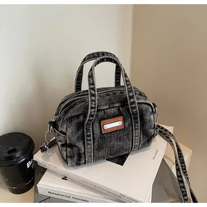Close-up of vintage denim shoulder bag showing leather patches and metal hardware details