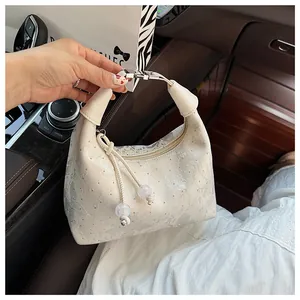 Macro shot of rhinestone butterfly bow and grey abstract texture on cream hobo bag