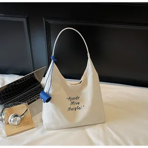 Détail du sac fourre-tout en toile minimaliste avec typographie bleue et petite pochette
