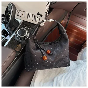 Detail of black jacquard handbag with polka dots and amber bead tassel in car interior