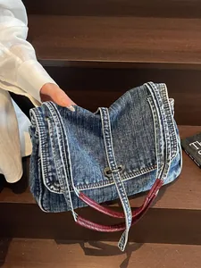 Vintage denim shoulder bag with red leather handles and metal lock on a wooden stair