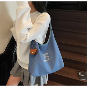 Gros plan du sac fourre-tout bleu en toile avec mini pochette en cuir sur un escalier
