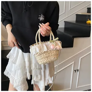 Détail du bord en dentelle et bandoulière perle du sac en paille avec tulipes roses