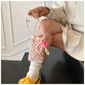 Detail of hand-knitted tulip phone bag featuring pearl charm and floral crochet texture