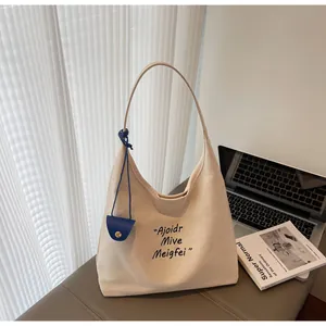 Détail du fourre-tout en toile beige avec mini pochette bleue et typographie artistique
